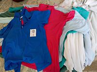 Stack of assorted women’s polo shirts in various colors
