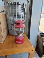 Front view of Coleman red camping lantern showing globe, burner and logo
