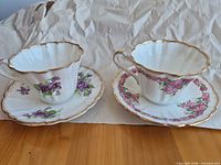 Front view of both teacups on saucers showing floral patterns and gold trim