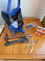 Overview of lot on table showing tote, hammer, lever tool, wrench, staples box, nails container