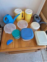 Group shot of entire lot on wooden table showing all pitchers, watering cans, and containers