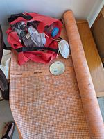 Roll of orange grid underlayment with tote, respirator and round metal cover visible