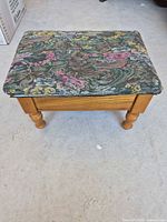 Closed ottoman showing floral tapestry top and wood frame