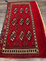 Full view of handmade red Turkman wool rug showing overall pattern and size