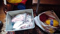 Plastic tote containing individually packaged white 3M N95 masks next to bag of assorted yarn