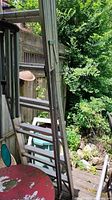 Side view of aluminum extension ladder leaning against fence