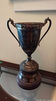 Full view of silver-plated trophy on wooden base