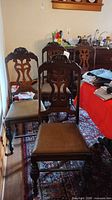 Three of the six carved wood dining chairs, showing backs, seats and turned legs
