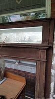 Full view of oak fireplace mantel and mirror leaning against wall