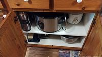 Cabinet shelf with travel tumbler, Breville slow cooker, rice cooker, mixing bowls, containers