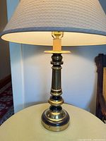 Full view of brass lamp with shade lit