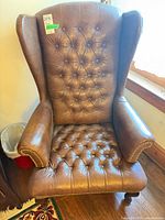 Front view showing full chair, tufting, nailhead trim, wooden legs