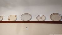 Five ceramic plates displayed on shelf
