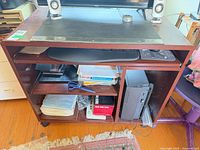 Front view of desk showing keyboard tray, open shelving and casters