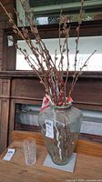 Large green-tinted glass vase with branches beside cut crystal tumbler