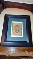 Full view of framed miniature rug tapestry on chair