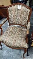 Front view of armchair showing upholstery pattern, wood frame and nailhead trim