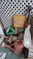Lot overview showing watering can, shovel, axe, broom, folding trays, tubs, pots