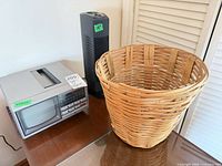 GE portable TV/radio, Lasko tower fan, wicker basket on table