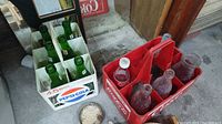 Coca-Cola crate with clear and purple-tinted bottles, metal bottle caps nearby
