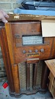 Front view of Marconi console radio showing cabinet, dial, speaker grille, buttons and wear