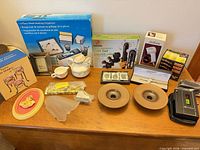 Wide view of tabletop items including massager, organizer, ceramics, votive holders, cassette player, books and other boxed items