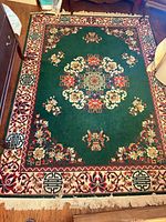 Full view of green medallion floral area rug with fringe