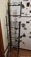 Full view of black metal etagere beside refrigerator