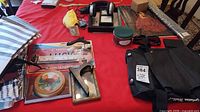 Lot overview on table showing headphones, frames, license plate, Bananagrams pouch, sunglasses, fabrics, tin, bag