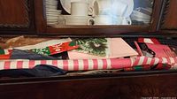 Drawer containing various wrapping supplies including striped paper roll, folded tissue, gift bags