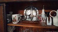 Overall cabinet view showing mug, silverplate pieces, trays, stemware