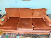 Front view of orange velvet three-seat sofa