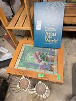 Lot overview showing atlas, stained glass item from other lot, and two wire baskets