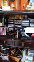 Shelf unit with audio CDs in racks, camera, pouch, cables, drawers