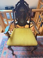 Front view of armchair showing cane back and upholstered seat