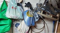 Wide view showing hanging blue clogs, black skates, plastic bags, cords