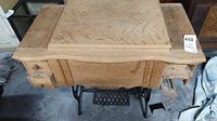 Top and front view of oak treadle cabinet with drawers and cast-iron base