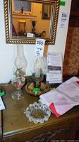 Overall lot on table showing both oil lamps, hobnail dish, folded flag