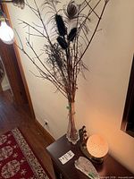 Lamp, vase with feathers, paperweight on table