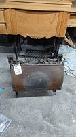 Front view of fireplace insert showing hinged front plate and grate filled with coal pieces