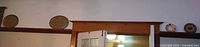 Wide view showing four decorative plates on shelf above doorway