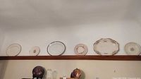 Six assorted plates and one display plate displayed on shelf