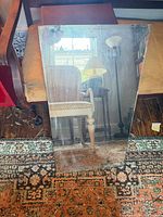 Front view of frameless mirror on rug shows size and surface scratches