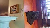 Both items on wall: framed toucan tile and cherub corbel