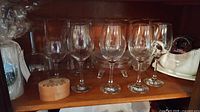 Cabinet shelf with six wine glasses, crystal dish, wooden trinket box and compote visible