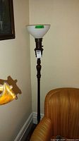 Full view of floor lamp beside chair showing entire height and wood post