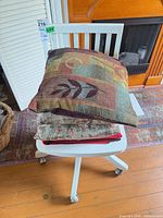 Stacked pillows and blanket on white swivel chair