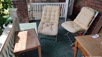 Overall view of wooden table and two lounge chairs on porch