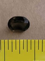 top view of oval faceted smoky topaz beside ruler for scale