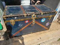 front view of metal steamer trunk showing brass hardware and decals